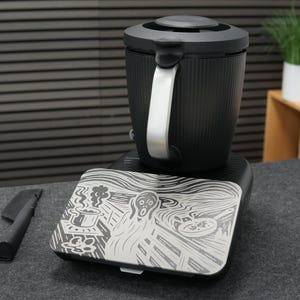 以下が含まれることがあります： シルバーのハンドルと蓋が付いた黒い電気ケトル。ベースには、エドヴァルド・ムンクの絵画「叫び」のグラフィックが描かれています。左側には黒いアクセサリーがあります。高さ約20cm。