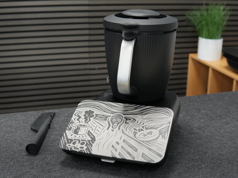 以下が含まれることがあります： シルバーのハンドルと蓋が付いた黒い電気ケトル。ベースには、エドヴァルド・ムンクの絵画「叫び」のグラフィックが描かれています。左側には黒いアクセサリーがあります。高さ約20cm。