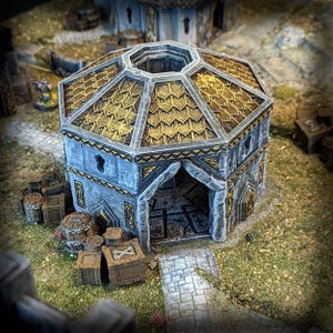 May include: A miniature fantasy building with a gray stone exterior and a gold-colored, octagonal roof. The building has an arched entrance and is surrounded by miniature crates and barrels. The scene is set on a grassy surface.