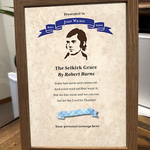 May include: A framed print of a poem titled "The Selkirk Grace" by Robert Burns. The poem is printed on a parchment-like background with a blue ribbon at the top. The ribbon has the words "Burns" and "Supper" on it. The poem is presented to John Wilson.