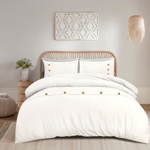 May include: White duvet cover with wooden button fastenings. The duvet cover is on a bed with white pillowcases and a wooden headboard.