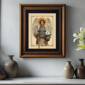 May include: A framed print of a painting depicting an angel with wings, holding a staff and a white flower. The angel is wearing a blue and white tunic and has a halo.