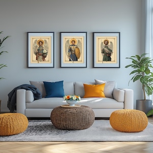 May include: Three framed prints of angels with wings, each with a different pose and background. The prints are hung on a light grey wall above a white sofa with blue and orange throw cushions.