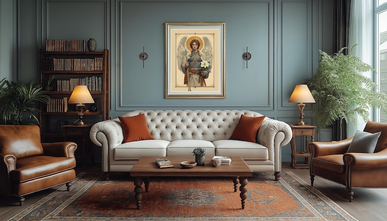 May include: A white sofa with two orange throw cushions sits in a living room with a framed painting of an angel holding flowers. The room has a blue wall, a wooden bookcase, and a brown leather armchair.