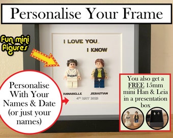 May include: A white picture frame with a black mat and a white background. The frame is personalized with two Lego minifigures, the text "I LOVE YOU... I KNOW", and the names "Annabelle" and "Sebastian" with the date "4th May 2023". The frame is also accompanied by a free 15mm mini Han & Leia in a presentation box.