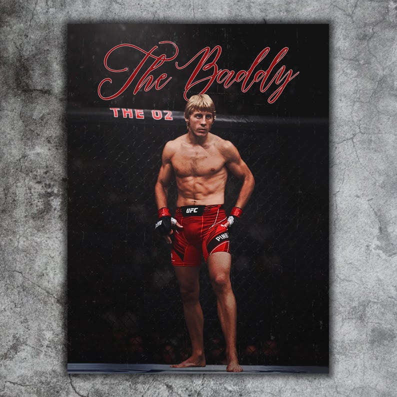 Puede incluir: Un p&oacute;ster con un atleta sin camisa con pantalones cortos rojos y guantes negros, de pie en un ring de lucha. El texto "The Baddy" est&aacute; escrito en escritura roja encima del atleta, con "THE OZ" debajo.
