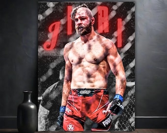 May include: A mixed martial arts fighter with a beard and a shaved head stands in a fighting ring. He is wearing red and black fighting shorts with the word "PRO