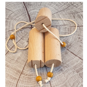 May include: Three wooden rollers with a string and yellow beads attached. The rollers are connected by the string and have a groove cut into the top and bottom of each roller.