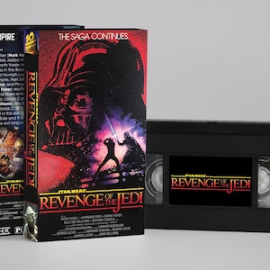 May include: Three VHS tapes of "Star Wars: Revenge of the Jedi" with the text "The Empire Falls" and "The Saga Continues". The tapes are black with colourful movie artwork and text. A single VHS tape is also visible.