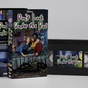 Op de afbeelding: Een VHS-band en hoes voor de Disney-film "Don't Look Under the Bed". De hoes toont een filmposter met drie mensen en de titel in groene druipende letters. De VHS-band is zwart.