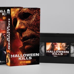 Peut inclure: Une cassette VHS noire et son étui en carton assorti présentant le titre du film Halloween Kills. La couverture affiche un gros plan d'un masque usé sur un fond rouge et orange ardent avec le texte Let It Burn et Blumhouse.
