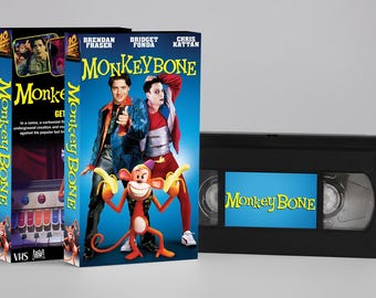 May include: A VHS tape and box set for the movie "Monkeybone." The box art features Brendan Fraser, Bridget Fonda, and Chris Kattan, with a cartoon monkey holding bananas. The VHS tape has the movie title on a blue background.