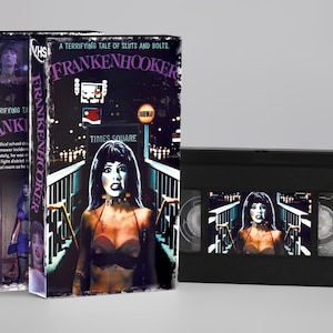 Peut inclure: Une cassette VHS noire et son étui en carton présentant le titre du film Frankenhooker en violet. La couverture illustre une femme dans un décor sombre avec le texte A terrifying tale of sluts and bolts et Times Square visible.