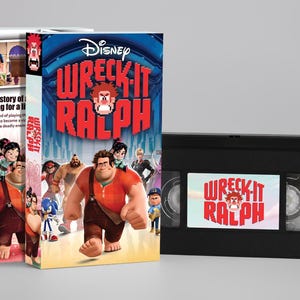 Op de afbeelding: Een Disney "Wreck-It Ralph" VHS-band en de bijbehorende doos. De doos toont een kleurrijke illustratie van de personages uit de film, met de titel in grote, vette letters. De VHS-band is zwart met een bijpassend etiket.