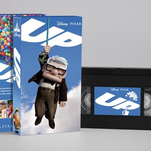Può includere: Una videocassetta VHS Disney Pixar Up e la sua custodia in cartone. La custodia blu presenta il titolo Up, un gruppo di palloncini colorati e l'illustrazione di un uomo anziano con gli occhiali. La cassetta VHS nera ha un'etichetta blu con il titolo Up.