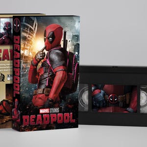 Op de afbeelding: Een Deadpool VHS-band met bijbehorende kartonnen hoes. De hoes toont het personage in een rood pak, het Marvel Studios-logo en de titel DEADPOOL in rode letters. De zwarte plastic VHS-band heeft een Deadpool-afbeelding op het etiket.