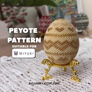 Puede incluir: Un huevo con cuentas crema y doradas con un patr&oacute;n geom&eacute;trico, exhibido en un soporte dorado. La imagen incluye el texto "PEYOTE PATTERN SUITABLE FOR MIYUKI" y "SYLIANKY.ETSY.COM".