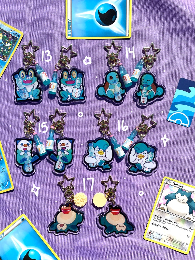 May include: A set of 10 clear acrylic keychains featuring different Pokemon characters drinking a blue beverage. Each keychain has a gold star charm and a gold ring.