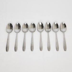 May include: Eight silver teaspoons with a floral design on the handle.