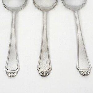 May include: Three silver soup spoons with a decorative floral design at the base of the handle. The spoons have a classic, elegant design, suitable for formal dining. The spoons are made of a shiny, reflective metal.