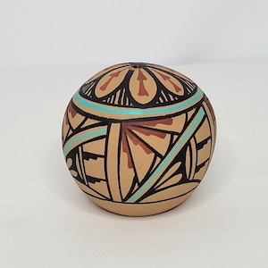 May include: A small, round, ceramic pot with a brown, black, and turquoise geometric design.