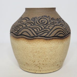 May include: A brown ceramic vase with a wavy pattern in a darker brown glaze. The vase has a rounded body and a wide opening.