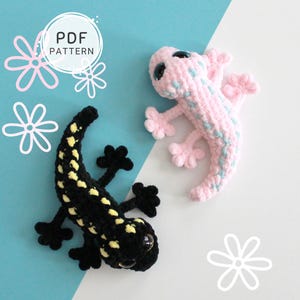 May include: Two crocheted salamanders, one black with yellow spots and the other pink with blue accents, are displayed on a blue and white background. The image includes the text "PDF PATTERN" in a circle, along with flower illustrations.