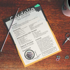 Printed pattern on a table surrounded by crochet supplies.