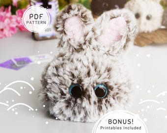 May include: A plush bunny with gray and white fur, pink inner ears, and sparkly blue eyes. The bunny has a round body and upright ears. Text on the image reads "PDF PATTERN" and "BONUS! Printables Included".
