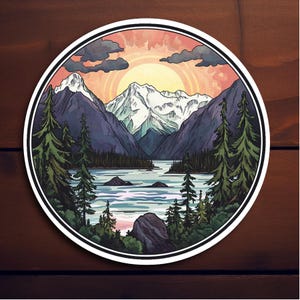 May include: A circular sticker with a scenic mountain landscape. The sticker features a lake with a mountain range in the background, a sunset sky with clouds, and a forest of pine trees in the foreground.