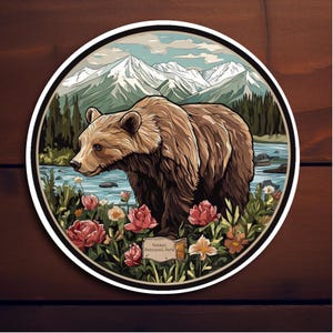 May include: A brown bear stands in a field of flowers with a river and mountains in the background. The text "Glacier National Park" is on a sign in the lower right corner.