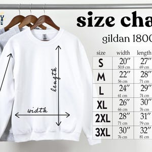 May include: A white Gildan 18000 sweatshirt hanging on a rack, with a size chart to the right. The chart shows measurements for width, length, and sleeve length in inches for sizes S through 3XL. The brand logo is in the upper left corner.