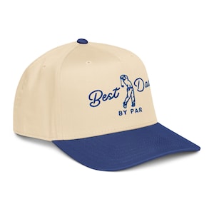 May include: A baseball cap with a cream-colored crown and a navy blue brim. The cap features the text "Best Dad BY PAR" in navy blue script and a golf swing illustration.