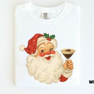 May include: White t-shirt featuring a vintage illustration of Santa Claus holding a cocktail. Santa is depicted with a red hat, white beard, and rosy cheeks. The cocktail has coffee beans on top. The word "White" is printed on the bottom right.