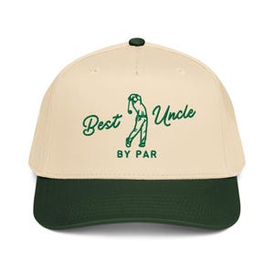 May include: A beige and dark green baseball cap with the text "Best Uncle By Par" in green script. The cap features a golf-themed graphic of a golfer in mid-swing. The brim is dark green.
