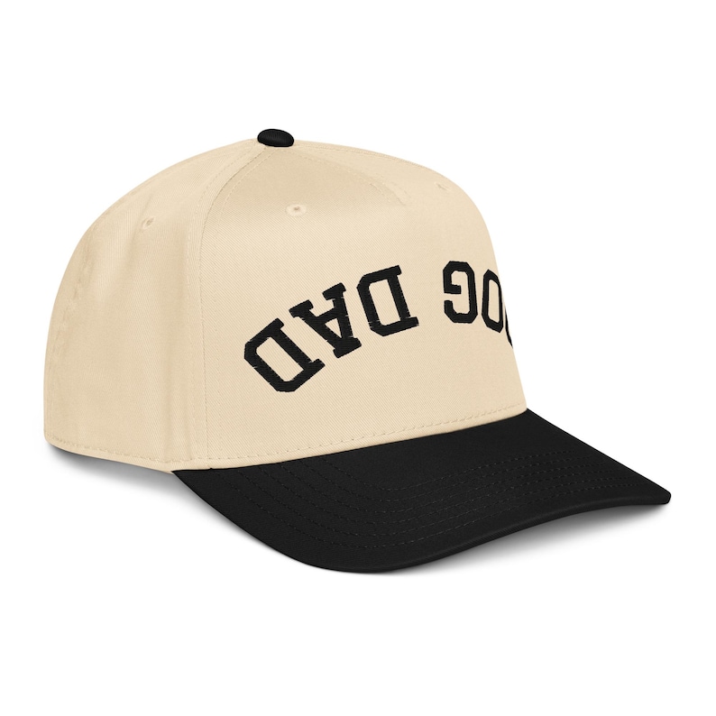 May include: Cream-colored baseball cap with a black brim. The cap features the embroidered text "DOG DAD" in black, arched across the front. A classic, casual accessory.