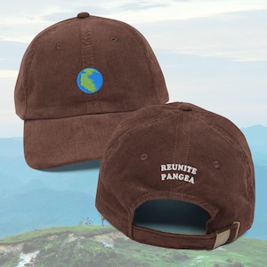 May include: Brown corduroy baseball cap with a small embroidered globe on the front. The back of the cap features the embroidered text "REUNITE PANGEA". The cap has a curved brim and an adjustable metal clasp.