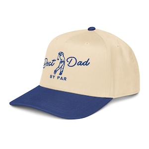 May include: A beige and blue baseball cap with the text "Best Dad BY PAR" in blue script. The cap features a golf-themed graphic and a curved brim.
