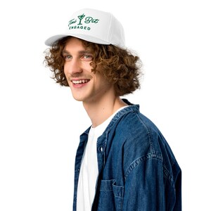Puede incluir: Gorra de b&eacute;isbol blanca con el texto "Tini Bit Engaged" en verde, con un gr&aacute;fico de copa de martini. La gorra la lleva una persona que viste una camiseta blanca y una camisa vaquera.