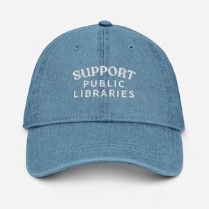 May include: A blue denim baseball cap with white embroidered text that reads "Support Public Libraries".