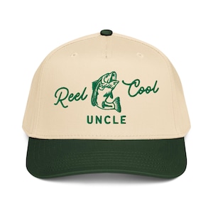 May include: A beige and dark green baseball cap with the words "Reel Cool Uncle" and a green fish graphic. The cap has a curved brim and a button on top. The text and graphic are in green.