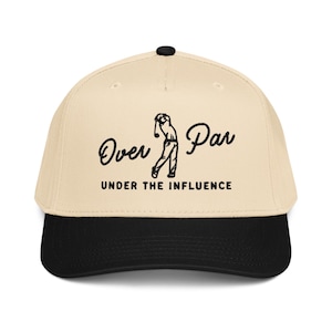 May include: A beige baseball cap with a black brim and a black button on top. The cap features the text "Over Par" in a script font, with a golfer graphic and the words "Under the Influence" below.