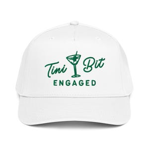 Puede incluir: Gorra de b&eacute;isbol blanca con el texto verde "Tini Bit Engaged" y un gr&aacute;fico de copa de martini. La gorra tiene una visera curva y un bot&oacute;n en la parte superior. Un accesorio divertido para una fiesta de compromiso.