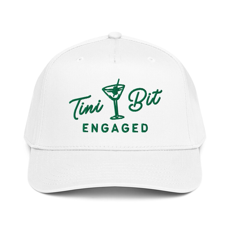 Puede incluir: Gorra de b&eacute;isbol blanca con el texto verde "Tini Bit Engaged" y un gr&aacute;fico de copa de martini. La gorra tiene una visera curva y un bot&oacute;n en la parte superior. Un accesorio divertido para una fiesta de compromiso.