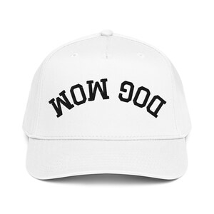 May include: White baseball cap with the text "DOG MOM" in black, arched across the front. The cap has a curved brim and a button on top. A casual accessory for dog lovers.