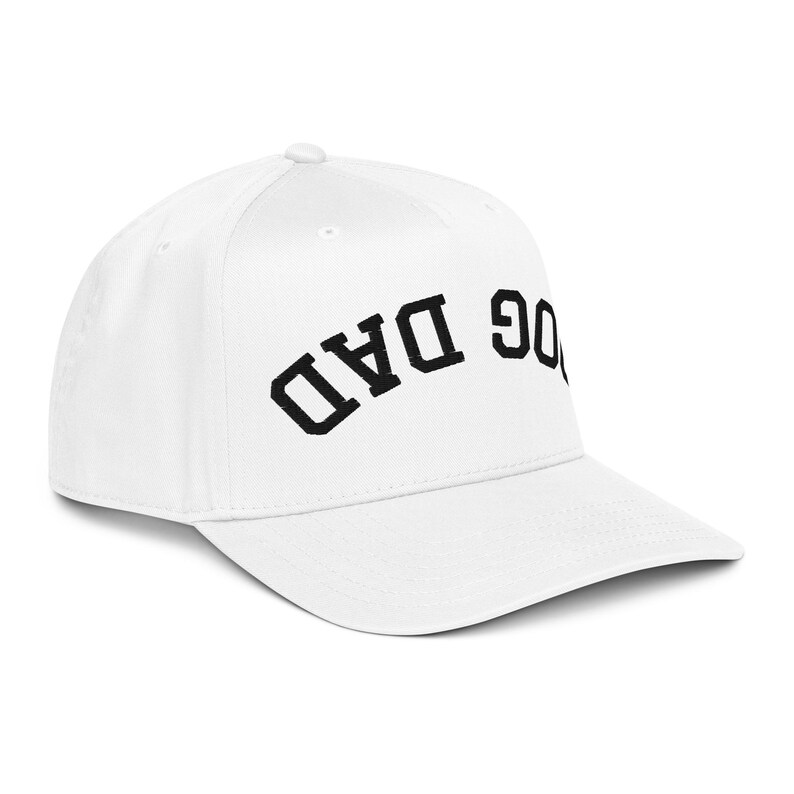 May include: A white baseball cap with a curved brim. The cap features the embroidered text "DOG DAD" in black, arched across the front. The hat is a classic style, suitable for casual wear.