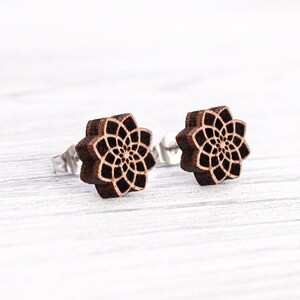 Könnte beinhalten: Ein Paar Holzohrringe mit einem detaillierten Mandala-Design. Die Ohrringe sind braun und haben einen silbernen Stift.