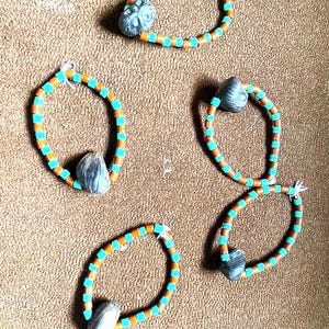 May include: Five bracelets made of brown and turquoise beads with a dark brown seed pod charm on each bracelet.