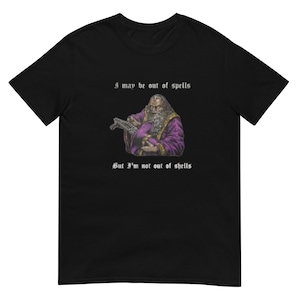 May include: A black t-shirt with a white graphic of a wizard holding a wand and a shell. The text on the shirt reads "I may be out of spells but I'm not out of shells".