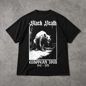 Puede incluir: Camiseta negra con un gr&aacute;fico blanco de una rata y el texto "Black Death" y "European Tour 1347-1351". El dise&ntilde;o tiene una est&eacute;tica vintage y g&oacute;tica.